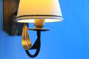 a lamp hanging on a blue wall with a white shade at Pousada do Cais in Paraty
