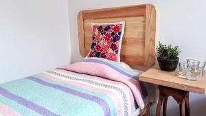a bed with a colorful blanket and a wooden headboard at Casa Gecko in Oaxaca City