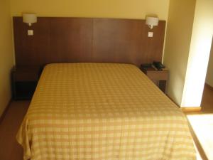 uma cama num quarto com um cobertor amarelo e branco em Hotel Minho Belo em Vila Nova de Cerveira