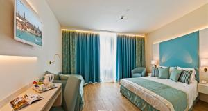 a hotel room with a bed and a chair and a desk at Hotel Montecarlo in Bibione