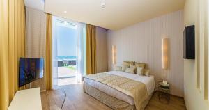 a bedroom with a bed and a television and a balcony at Hotel Montecarlo in Bibione