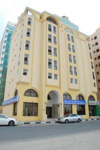 un bâtiment jaune avec des voitures garées devant lui dans l'établissement Al Buhaira Hotel Apartment, à Charjah