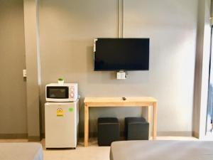 Zimmer mit einem TV und einem Tisch mit einer Mikrowelle. in der Unterkunft R9 Bangkok in Bangkok