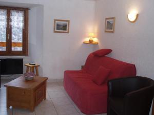 een woonkamer met een rode bank en een tafel bij L'ancolie in Orelle