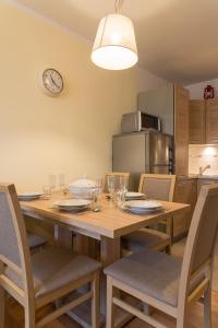 uma mesa de jantar com cadeiras e um relógio na parede em Apartament Na Urlop - Centrum - Przy Amfiteatrze - 500m do Basenów Wisła em Wisla