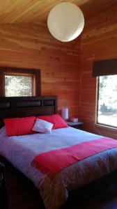Un dormitorio con una cama grande en una habitación de madera. en Cabaña en Caburgua, Pucon, en Pucón