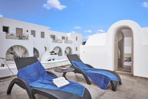two chairs and a table on a balcony with white buildings at La Bellezza Eco Boutique Hotel in Kamari