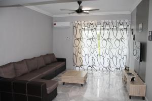 a living room with a brown couch and a window at Family Friendly Homestay @ Teluk Kemang Ocean View Resort in Kampong Tanah Merah