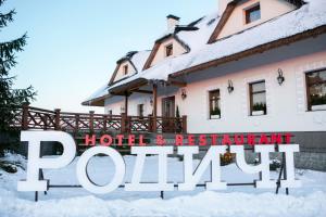 una casa nella neve con un cartello che legge il caveau dell'hotel e del ristorante di Родичі a Zhashkiv