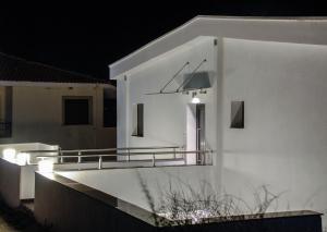 Casa blanca con balcón por la noche en Aelia Apartments, en Nea Peramos