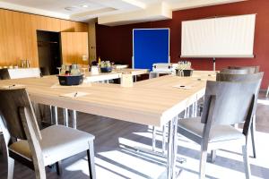 a conference room with a large wooden table and chairs at Hotel Sportwelt Radeberg in Radeberg +25 photos