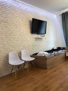um quarto com duas cadeiras brancas e uma televisão numa parede de tijolos em Pokoje nad Drzewiczką em Drzewica