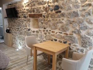 comedor con pared de piedra y mesa y sillas de madera en Studio mistral, en Valence