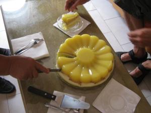 a person cutting a pineapple cake on a table at Amaryllis Hotel in Karpathos