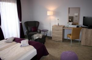 ein Hotelzimmer mit einem Bett und einem Stuhl in der Unterkunft DAS HUDEWALD Hotel & Resort in Ückeritz