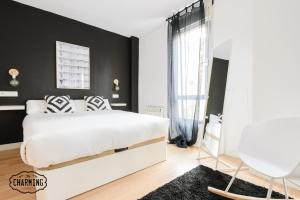 マドリードにあるCharming Puerta de Toledo IVの白いベッドと黒い壁のベッドルーム1室