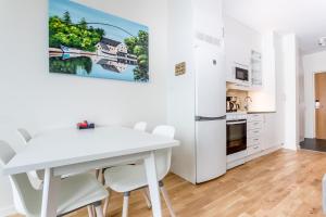 a white kitchen with a white table and chairs at ApartDirect Linköping Arena in Linköping