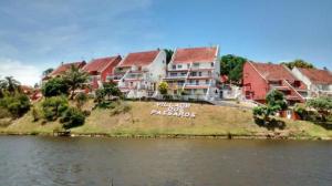 a group of houses on a hill next to the water at Village dos Pássaros Apartamento in Guarapari