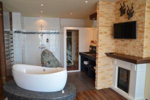 ein Bad mit einer Badewanne, einem TV und einem Kamin in der Unterkunft Seehotel Adler in Bodman-Ludwigshafen
