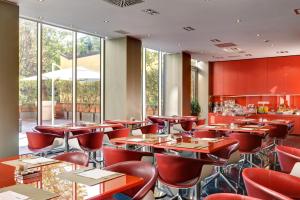 a restaurant with red chairs and tables and windows at UNAHOTELS Bologna Centro in Bologna