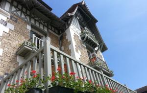 a house with flowers on the balcony of it at Villa Augeval Hôtel de charme & Spa in Deauville