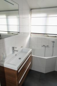 ein Badezimmer mit einem Waschbecken, einer Badewanne und einem Spiegel in der Unterkunft Hello Zeeland - Vakantiehuis Zwin 218 in Breskens
