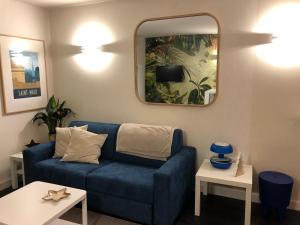a living room with a blue couch and a mirror at Emeraude, pleine vue de mer in Saint Malo