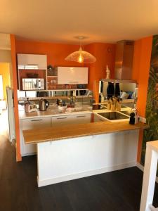 a kitchen with orange walls and a white counter top at Emeraude, pleine vue de mer in Saint Malo