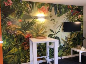 a wall mural of a jungle with a table and a tv at Emeraude, pleine vue de mer in Saint Malo