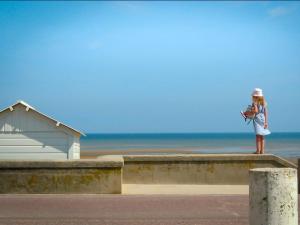 a woman standing on a wall near the beach at La Cantellerie in Courseulles-sur-Mer