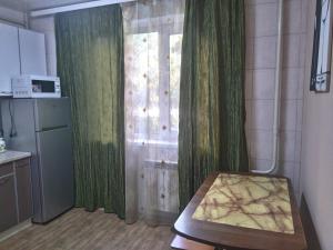 a kitchen with green curtains and a table in front of a window at Просторная 1комнатня квартира напротив ТРЦ Дафи Ашан рядом ресторан Альтбир in Kharkiv