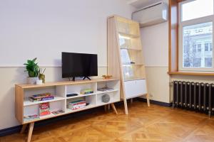 Town Hall Apartments في فيلنيوس: غرفة معيشة مع تلفزيون على رف كتاب