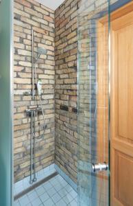 a bathroom with a glass shower with a brick wall at Town Hall Apartments in Vilnius +13 photos