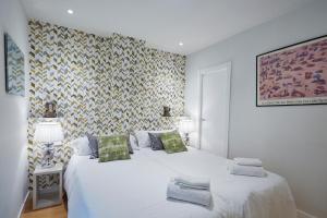 biała sypialnia z 2 łóżkami i ścianą w obiekcie LEEWAYS APARTMENT III in ALCALÁ 99 w Madrycie