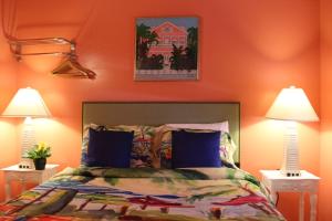 a bedroom with orange walls and a bed with two lamps at Caribbean House, No Resort Fees in Key West