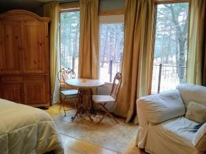 Bed and breakfast suite at the Wooded Retreat في Pine City: غرفة نوم مع طاولة وأريكة ونافذة