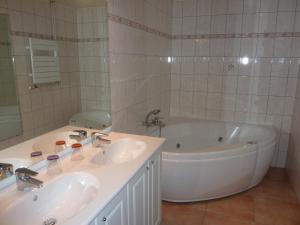 a white bathroom with two sinks and a tub at Chez Norbert in Bergheim