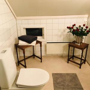 a bathroom with a toilet and a vase of flowers at A Noi Rooms in Kragerø +22 photos