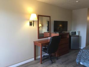 a hotel room with a desk and a mirror at Travel Inn - Mesa in Mesa