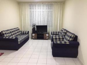 a living room with two chairs and a television at Sri Nabalu Apartment Platinum Putatan in Kota Kinabalu