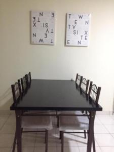 a dining room table with chairs and clocks on the wall at Sri Nabalu Apartment Platinum Putatan in Kota Kinabalu