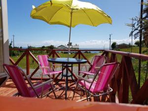 a table with chairs and an umbrella on a deck at Cabañas Agua Viva in Puerto Montt