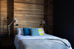 a bed with a wooden headboard and pillows at The Franklin Boutique Hotel in Adelaide