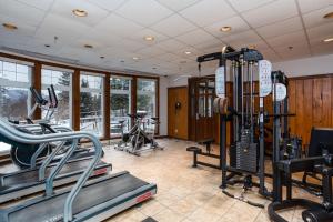 een fitnessruimte met loopbanden en fietsen in een kamer bij Tour des Voyageurs in Mont-Tremblant