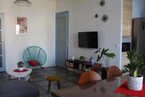 Una sala de estar con un sofá y un televisor. en Chez Marie Louise, en Pézenas