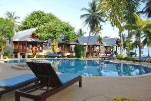 a resort with a pool and chairs and palm trees at Dewshore Resort in Ban Tai