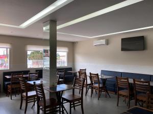 a dining room with tables and chairs and a tv at Sense Hotel Araucária in Araucária