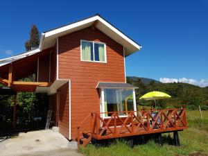 a house with a deck with an umbrella at Cabañas Agua Viva in Puerto Montt