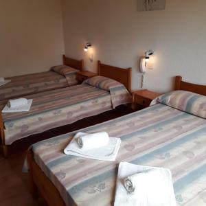 three beds in a room with towels on them at Hotel Mariska Dos Estrellas Superior in Villa Gesell