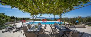 a patio with a table and chairs and a swimming pool at Apartmani Villa Athina in Tučepi